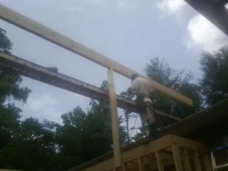 Carpenter setting a ridge beam over a new addition frame — Ice Dam Removal by Roofing Brothers in Glendale