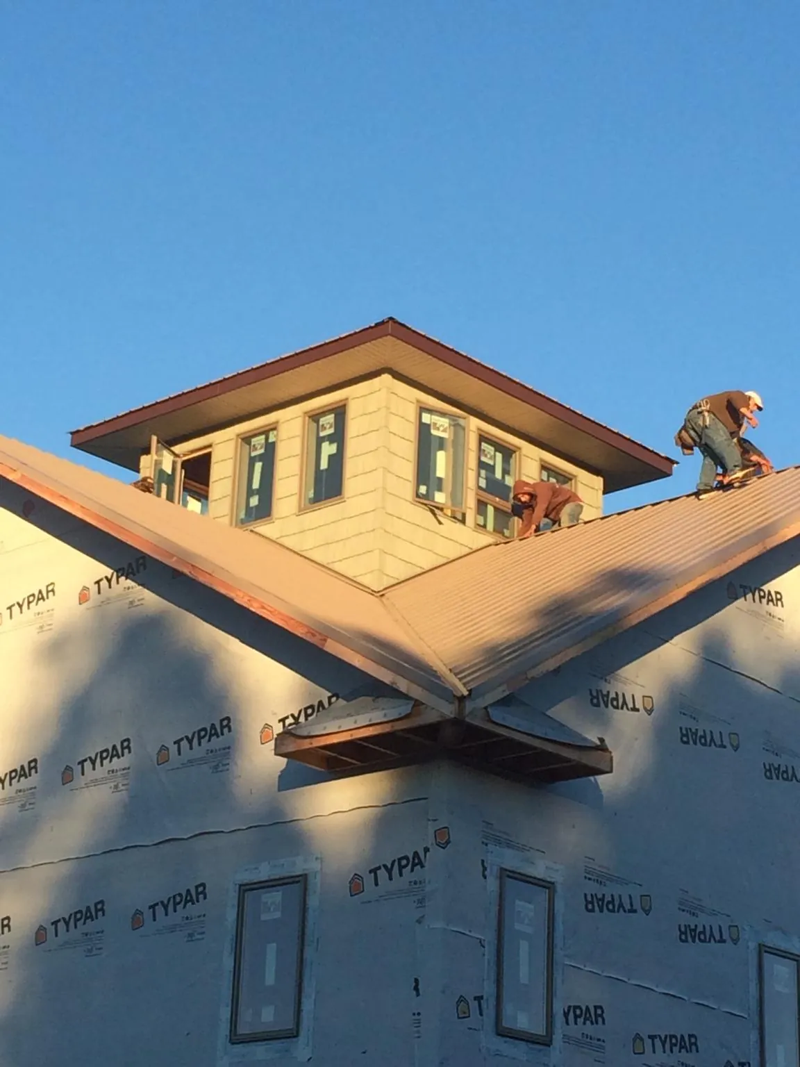 Roofers working around a rooftop cupola on a new metal roof at sunset — Roof Waterproofing in Glendale by Roofing Brothers